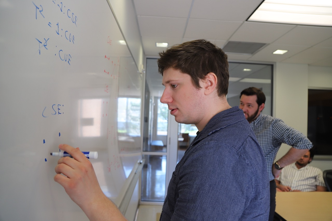 Michael Sizemore presenting quantum information work at a whiteboard